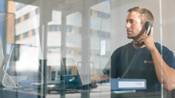 Un employé du service client elm.leblanc est au téléphone et regarde un écran d'ordinateur,